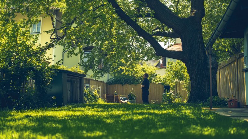 Grüner Garten mit großem Baum und Person im Hintergrund